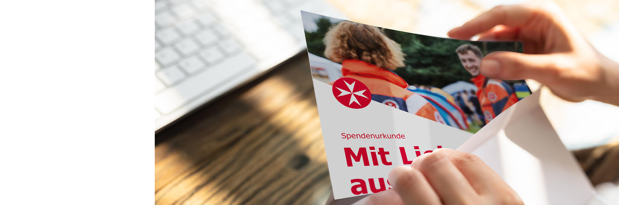 Zwei Hände ziehen eine Gutscheinkarte aus einem Briefumschlag