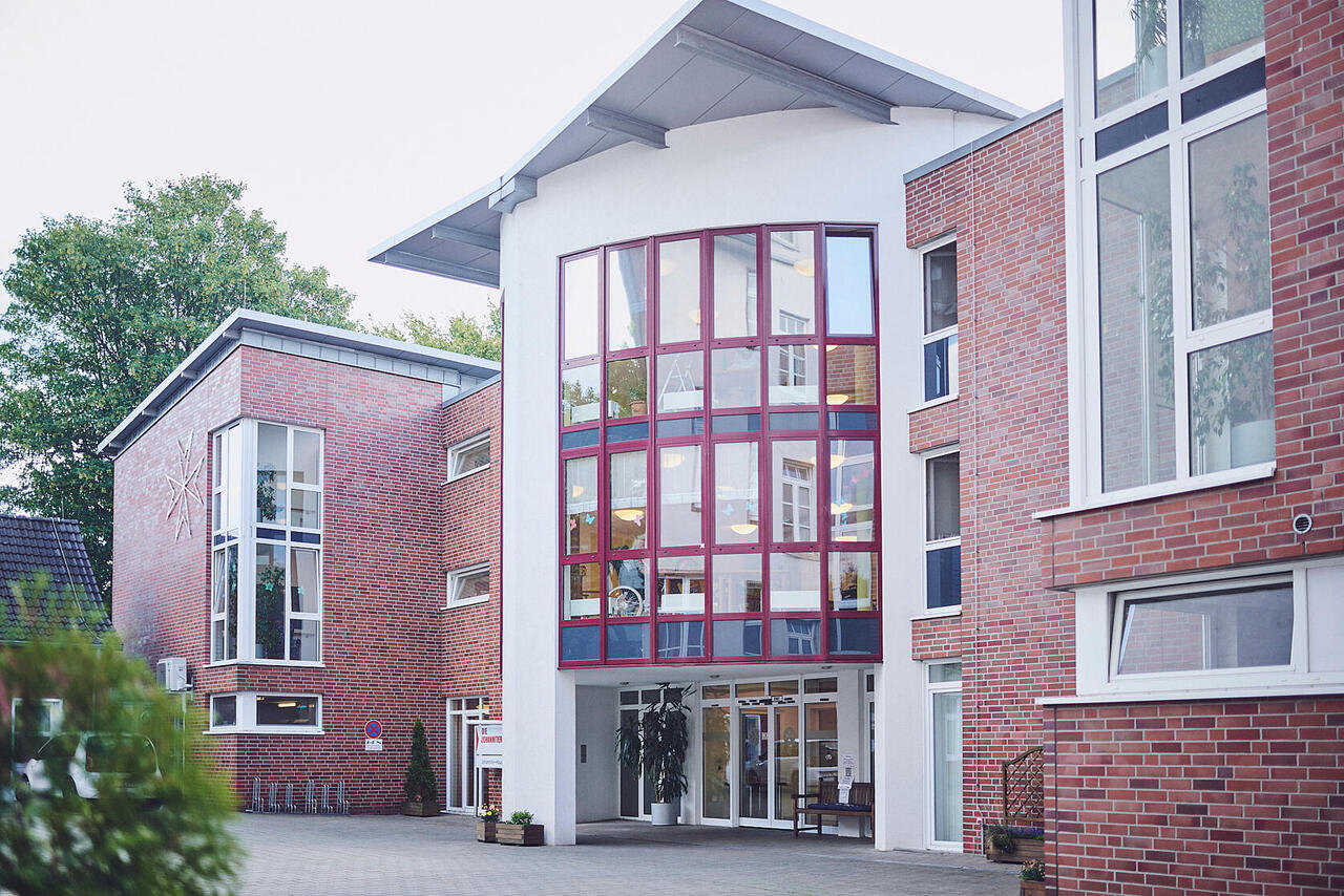 Der Haupteingang befindet sich in der Mitte des Hauses mit großen Fenstern und geschwungenen Dach