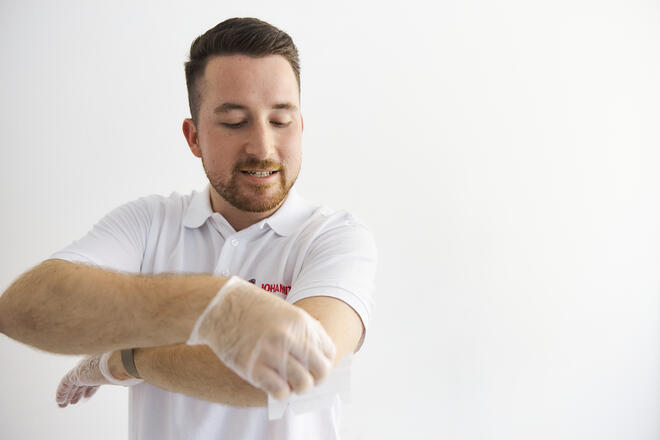 Ein Erste-Hilfe-Ausbilder der Johanniter zeigt, wie man eine Verletzung am Ellenbogen behandelt.