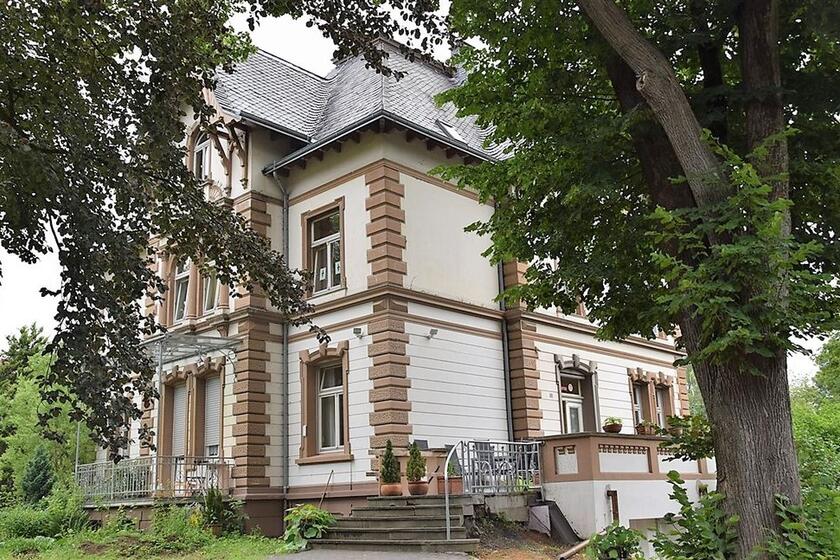 Eine alte Villa mit großen Bäumen.