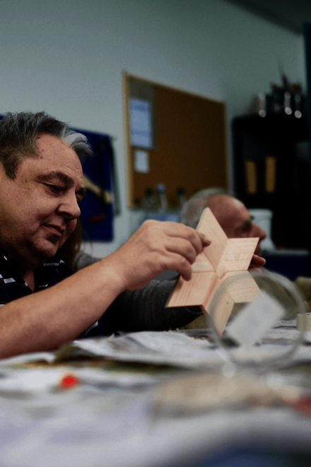 Ein Mann sitzt an einem Tisch und arbeitet an einem Stern aus Holz