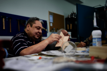 Ein Mann sitzt an einem Tisch und arbeitet an einem Stern aus Holz