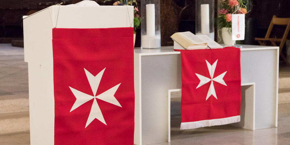 Rote Tücher mit weißem Johanniterkreuz schmücken Kanzel und Altar der Oberhofenkirche