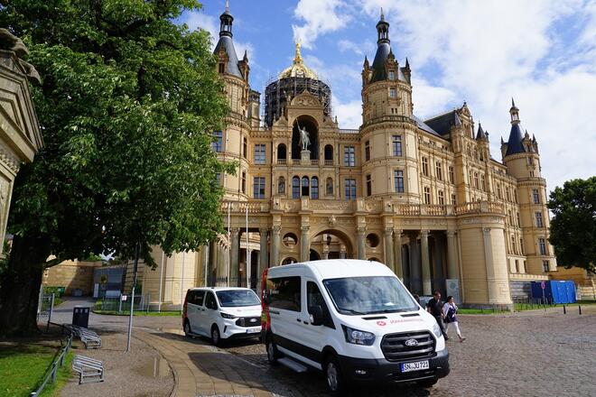 Zwei Autos der Johanniter stehen vor dem Schweriner Schloss