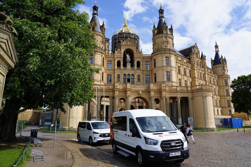 Zwei Autos der Johanniter stehen vor dem Schweriner Schloss