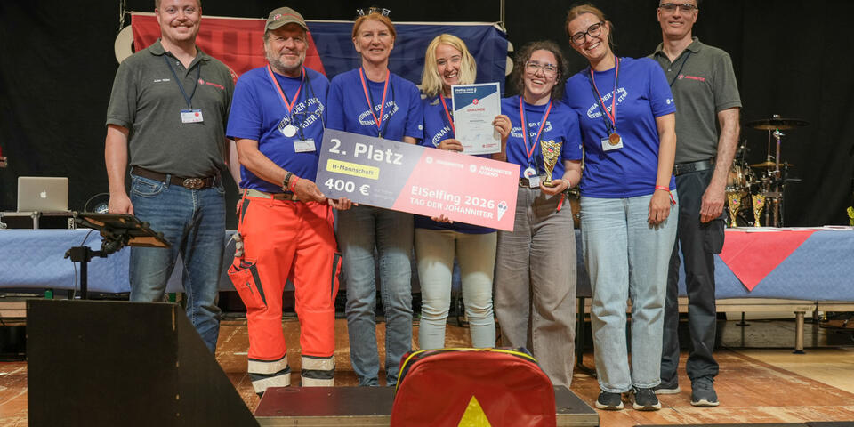 Preisverleihung am Tag der Johanniter: Team posiert mit Urkunde und Gewinn.