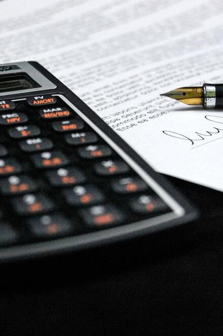 Taschenrechner und Füllfederhalter liegen auf einem unterschriebenen Dokument.