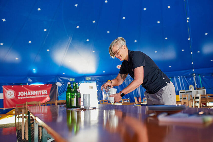 Eine Mitarbeiterin deckt einen Tisch im JUHte-Laune Zirkuszelt 