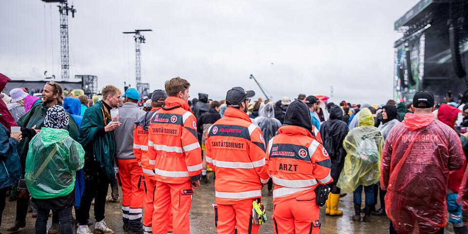 Mehrere Helfer schauen sich Konzert an in Regenkleidung