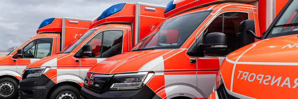 Vier moderne Rettungswagen der Johanniter stehen versetzt nebeneinander. 