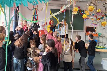Mehrere Betreuende führen Zaubertricks vor; Kinder schauen zu.