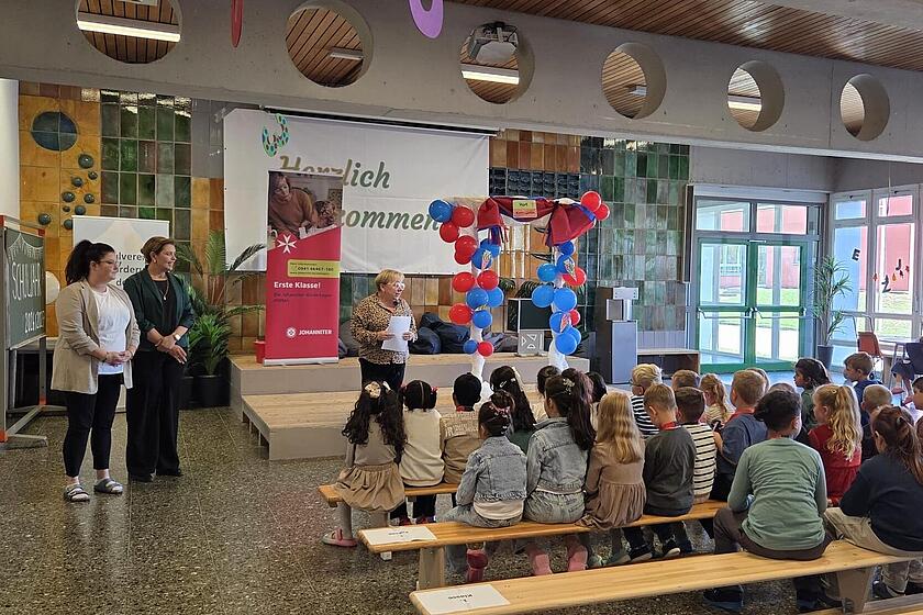 Kinder sitzen auf bänken und hören eine dame zu 