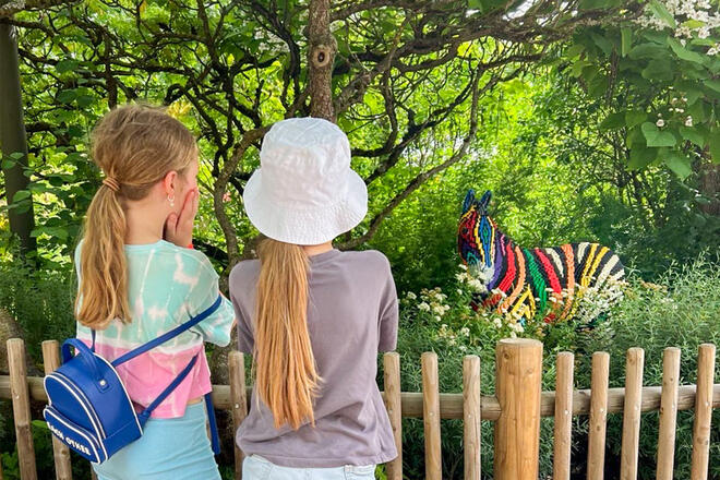 Zwei Kinder schauen über einen Zaun auf ein buntes Zebra aus Lego.