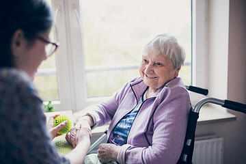 Ein grüner Igelball berührt die Hand der Seniorin im Johanniterhaus