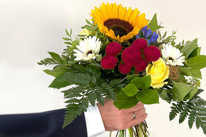 Glückwunsch mit Blumenstrauß zum Dienstjubiläum