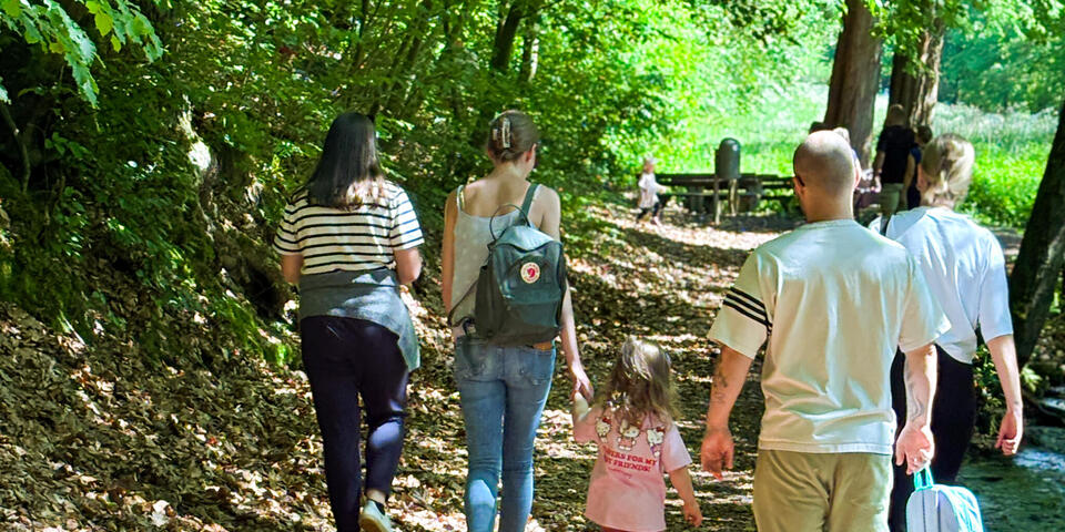Kinder und Erwachsene laufen auf einem Waldweg.