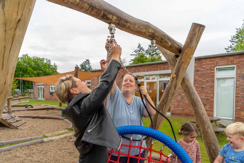 Tina Pötzl und Jenny Paape bringen die neue Nestschaukel auf dem Außengelände der Johanniter-Kita Kleine Hanseaten an.