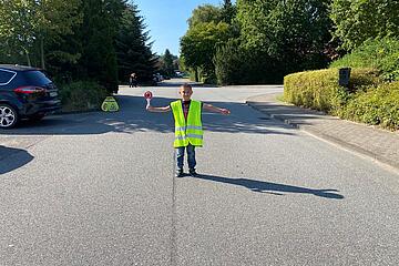Kind mit Warnweste auf Straße