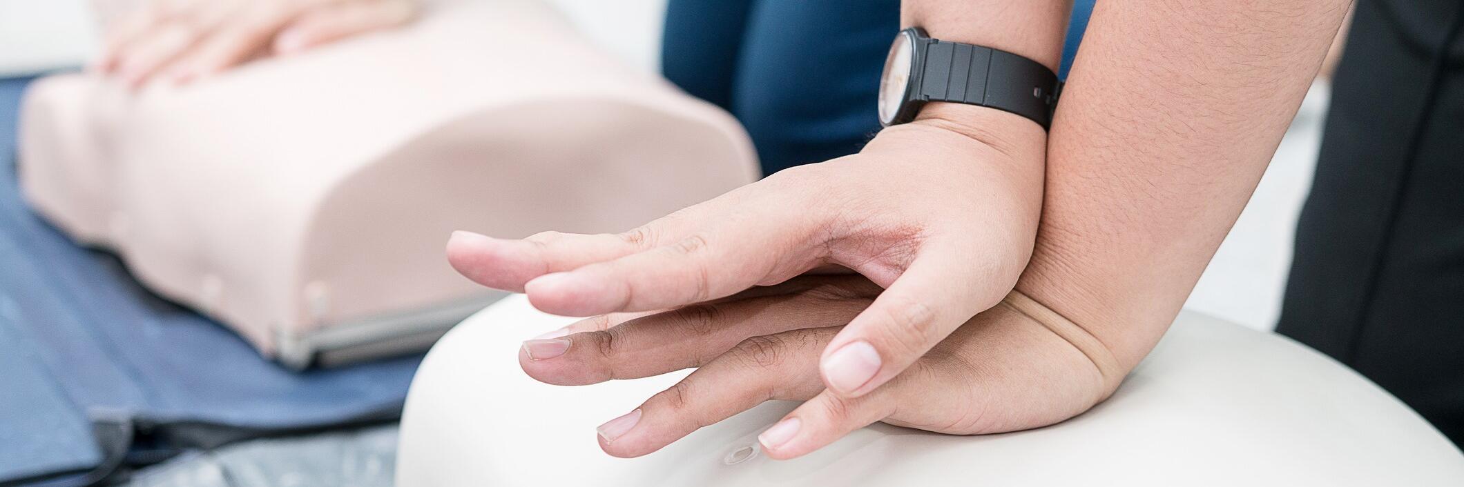 Teilnehmende eines Erste-Hilfe-Kurses üben die Reanimation an einer Puppe.