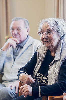 Drei Bewohnende lauschen einer Person im Gruppenangebot