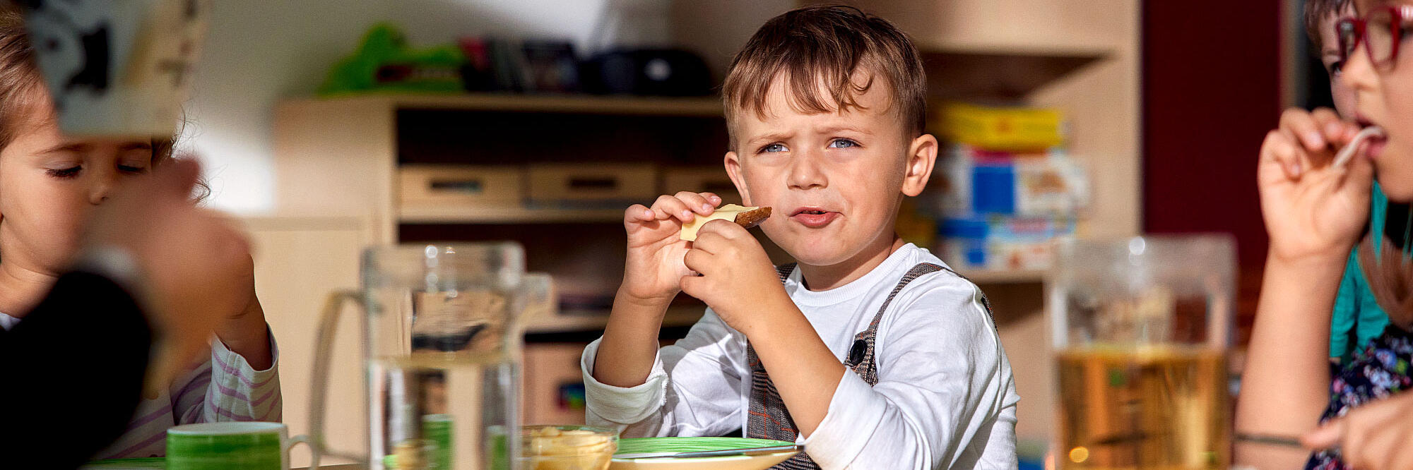 Ein Kind isst in einer Kita ein Brot.