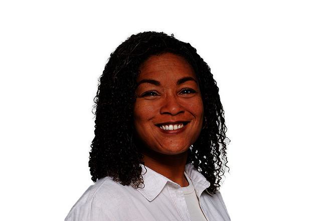 Frau mit dunklen Locken. Es sind Gesicht und Schultern sichtbar. Sie trägt eine weiße Bluse und lächelt in die Kamera