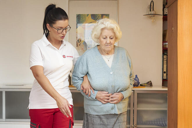 Johanniter Fachkraft weißt Seniorin auf Bodenunebenheiten in der Wohnung hin.