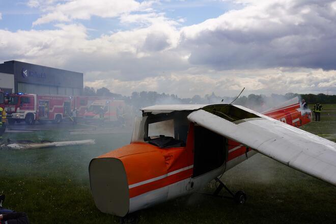 Rauchendes Propellerflugzeug bei einer Übung des Katastrophenschutzes auf dem Flugplatz