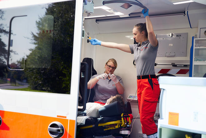 Versorgung im Rettungsdienst: Team legt Infusion bei Patientin im Krankentransport.