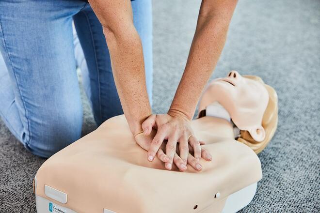 Eine Kursteilnehmerin übt die Reanimation an einer Übungspuppe.