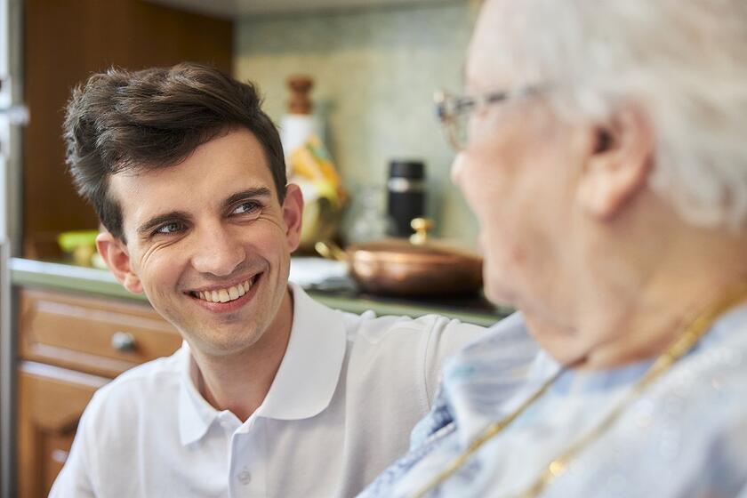 Ein Auszubildender in der Pflege betreut eine ältere Dame