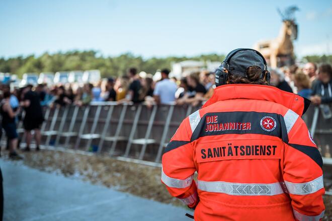 Ein Mitarbeiter des Sanitätsdienstes blickt auf eine Menschenmenge auf einem Festival