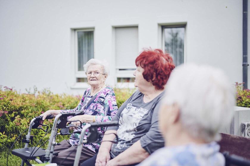 Drei Bewohnerinnen halten ein Schwätzchen an der frischen Luft