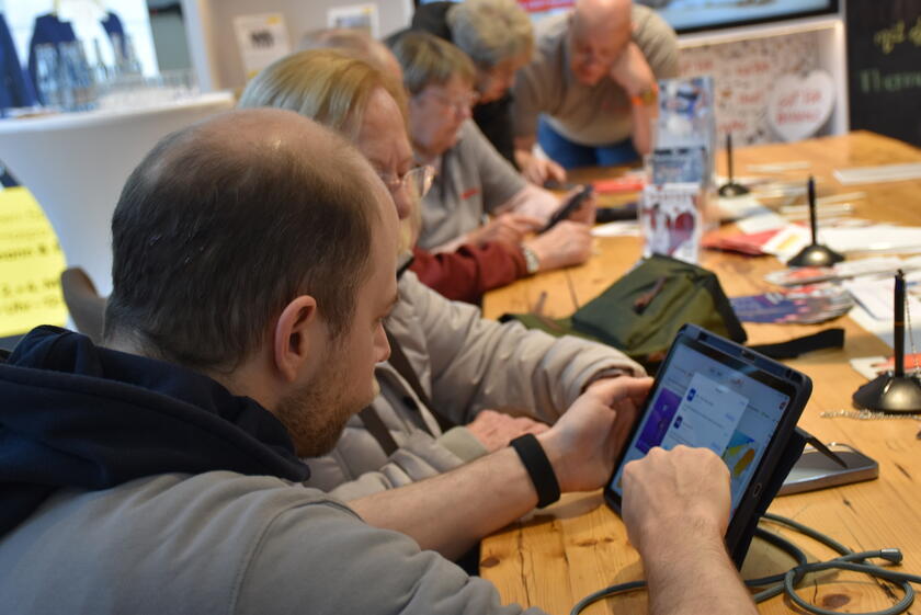 ein Mitarbeiter der Johanniter erklärt einer Seniorin die Funktionen ihres Tablets