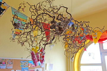 An diesen Zweig, der sich oben an der Decke befindet, hängen die Erzieherinnen die Schnuller der Kinder. Am Ende des Kita-Tages weden die Schnuller wieder runtergeholt und die Kinder nehmen sie mit nach Hause.