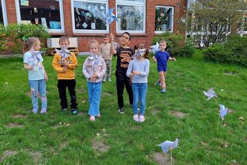 Kinder stehen vor der LUK und halten kleine Windräder in der Hand.