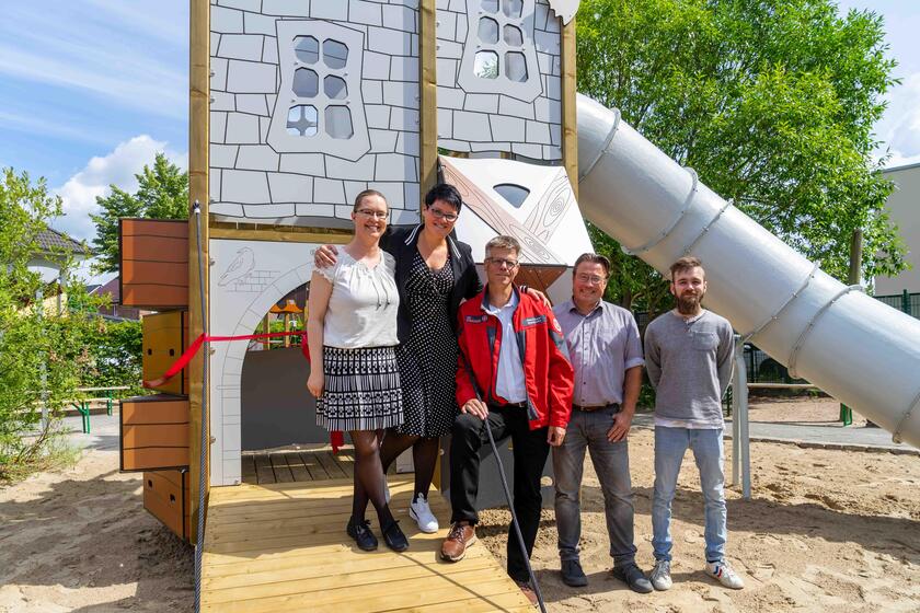 Auf dem Bild stehen fünf Personen vor der Ritterburg, einem Spielelement der Kita.