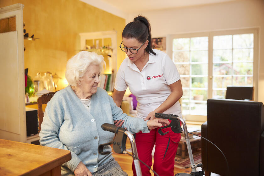 Pflegerin hilft Seniorin 