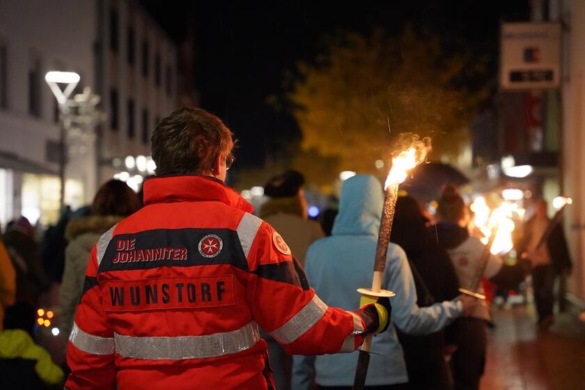 Ein Mitarbeiter der Johanniter in Wunstorf trägt eine Fackel durch die Innenstadt.