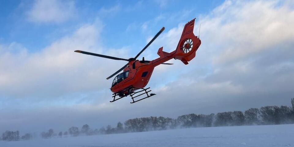 Rettungshubschrauber fliegt über eine Schneefläche