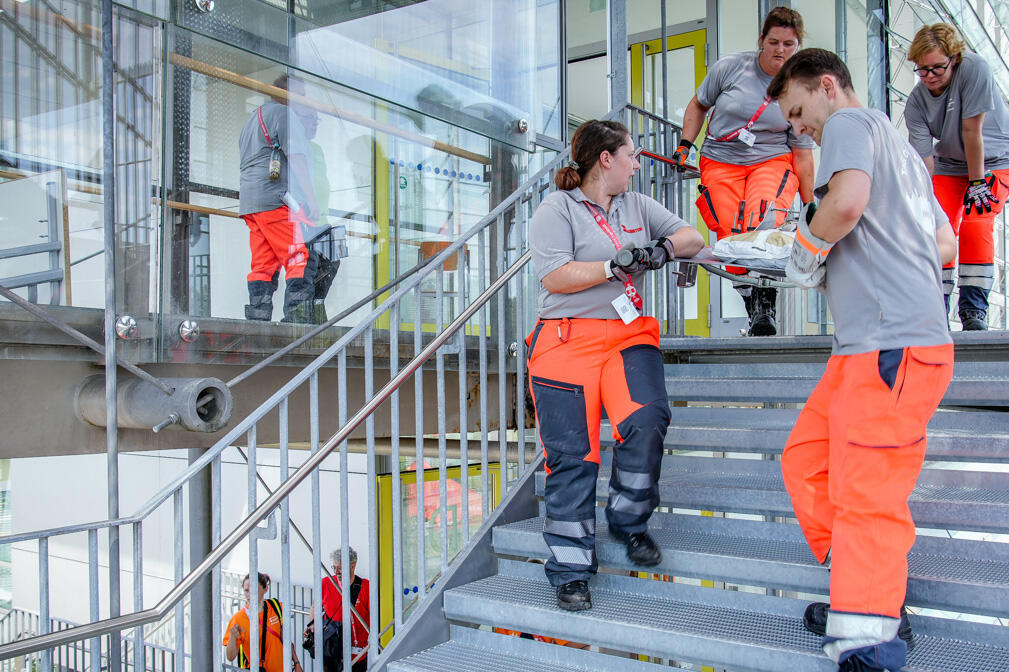 Rettungskräfte bringen eine beschwerte Trage eine Metalltreppe hinab.