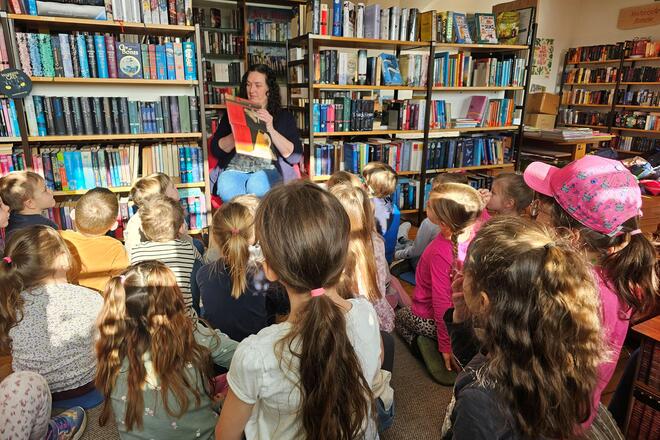 Büchereileiterin Tina Zeitler zeigt den Kindern ein Bilderbuch.