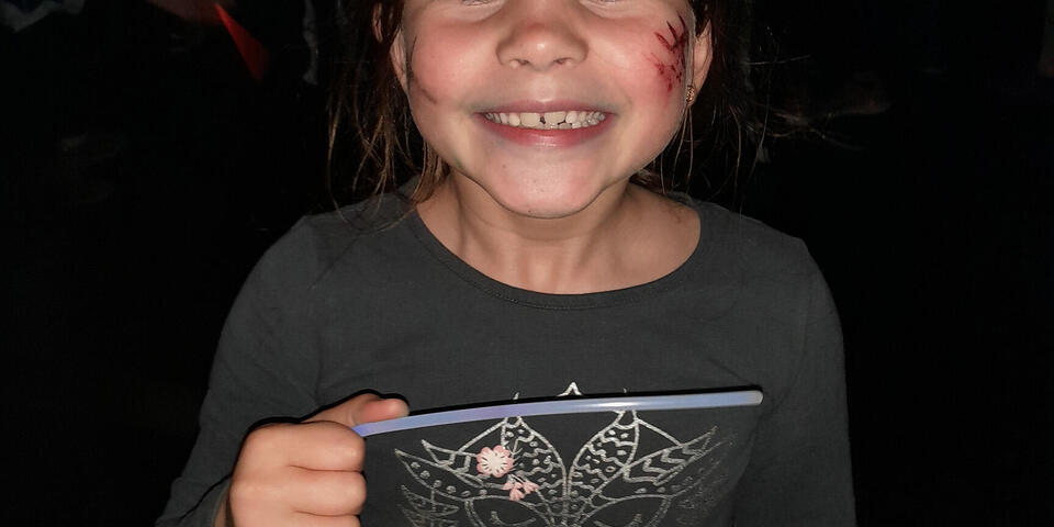 Ein lachendes Kind mit einer geschminkten Wunde an Halloween im Juhte-Laune-Zirkuszelt