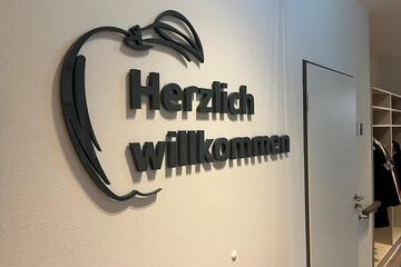 Schriftzug "Herzlich Willkommen" an einer weißen Wand