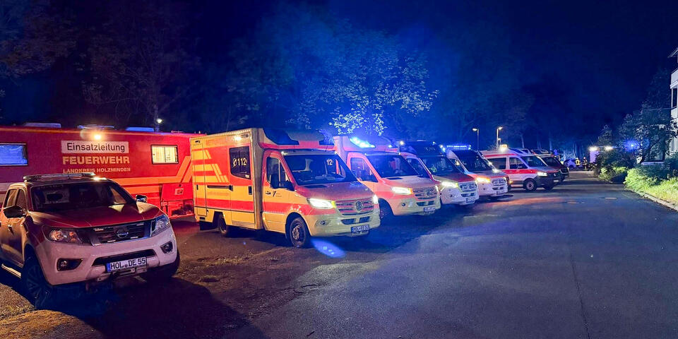 Einsatzfahrzeuge der Feuerwehr und der Johanniter in der Nacht auf einem Parkplatz