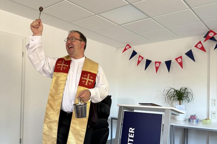 Abbildung: Pfarrer verteilt mit Weihwasser Segen.