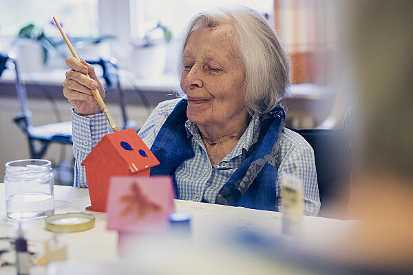 Eine Bewohnerin bemalt ein Vogelhäuschen