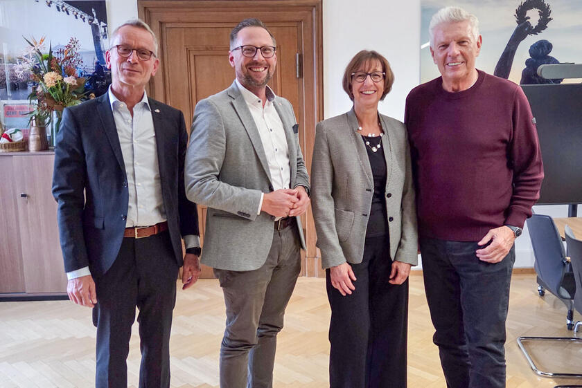 Oberbürgermeister Dieter Reiter steht in seinem Büro lächelnd neben den Boris Cramer, Susanne Lickert-Heinrich und Alfred Gahse von den Johannitern.