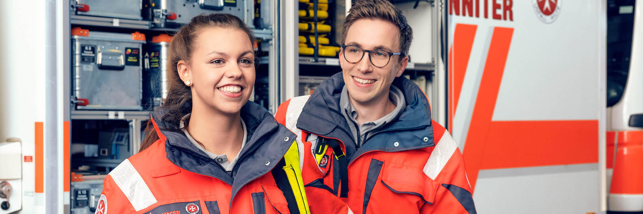 Zwei Einsatzkräfte stehen vor einem offenen Einsatzwagen