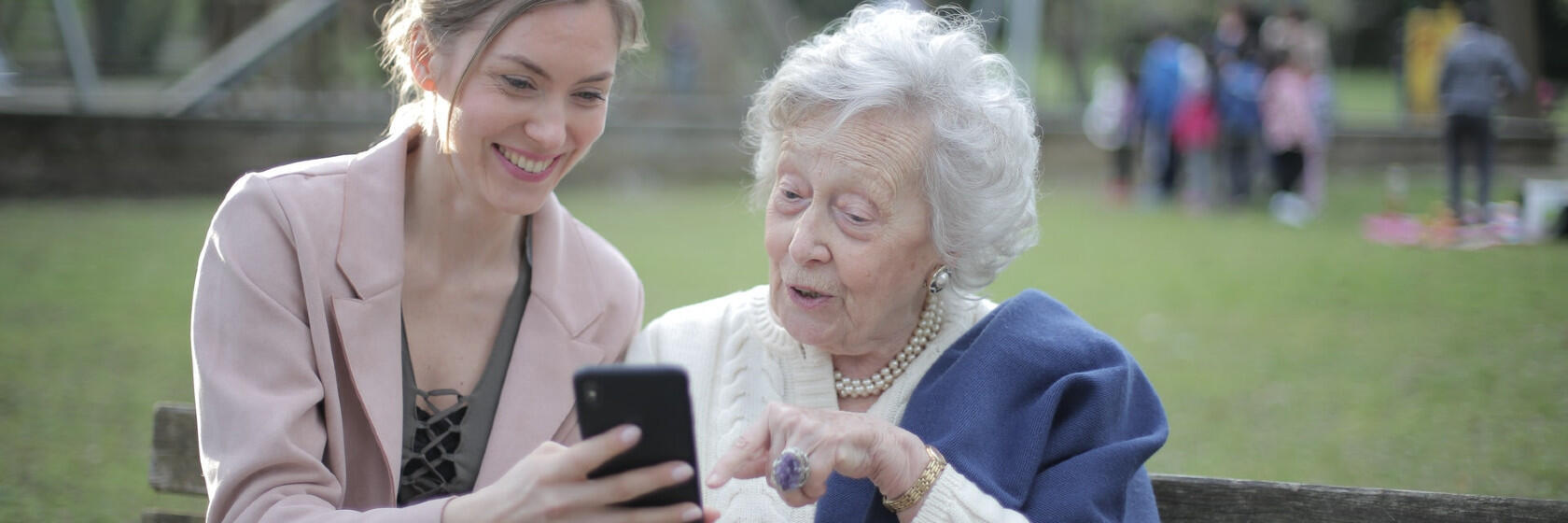 Eine junge und eine ältere Frau schauen gemeinsam auf ein Smartphone.